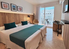 Ein Hotelzimmer mit zwei Betten, einem Schreibtisch, einem Stuhl, einem Fernseher und einem Balkon mit Blick.