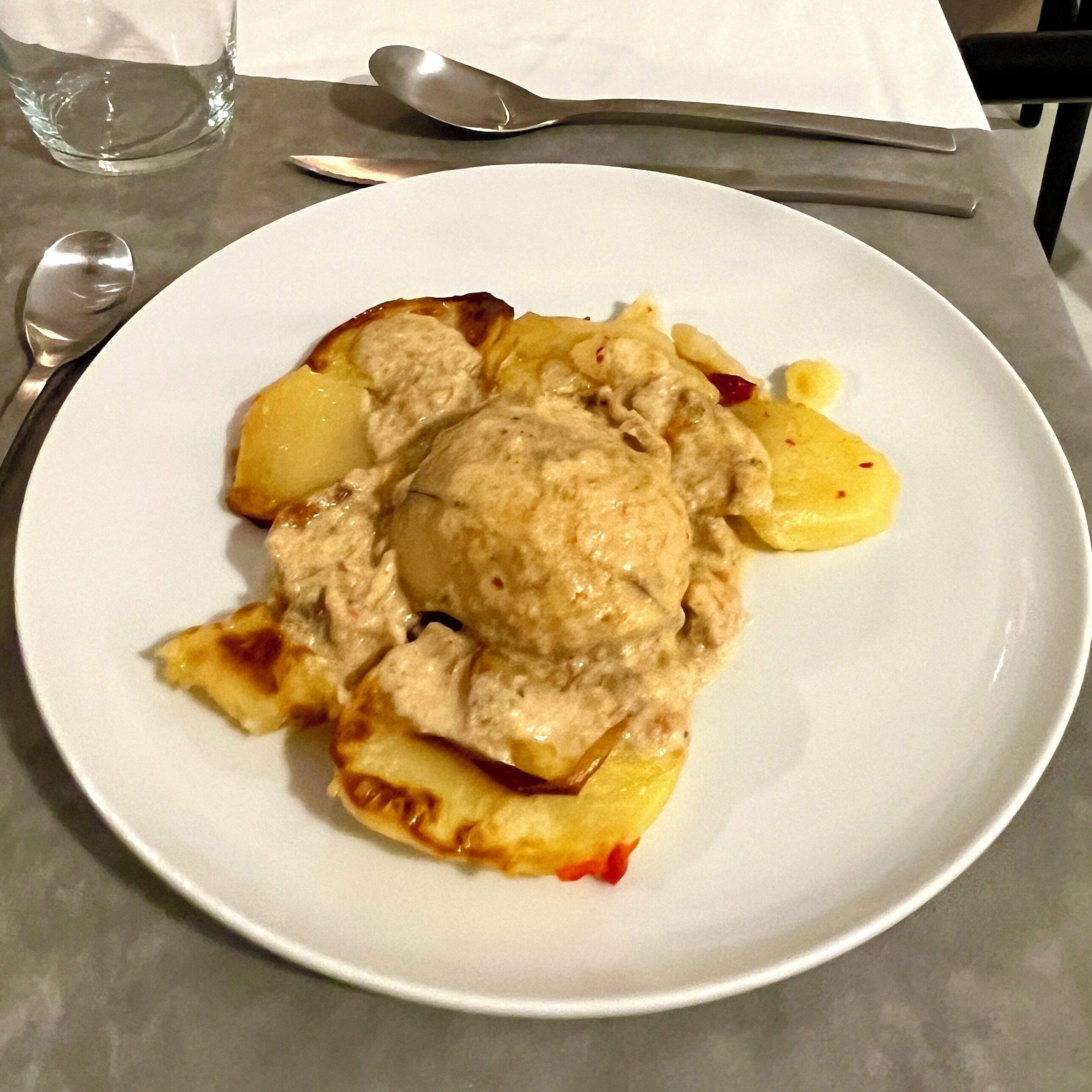Un plato de comida con un postre cremoso y fruta cortada sobre un plato blanco.