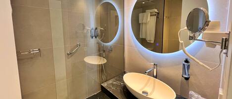A modern bathroom with a glass-enclosed shower, a vanity with a marble countertop, and two large mirrors.