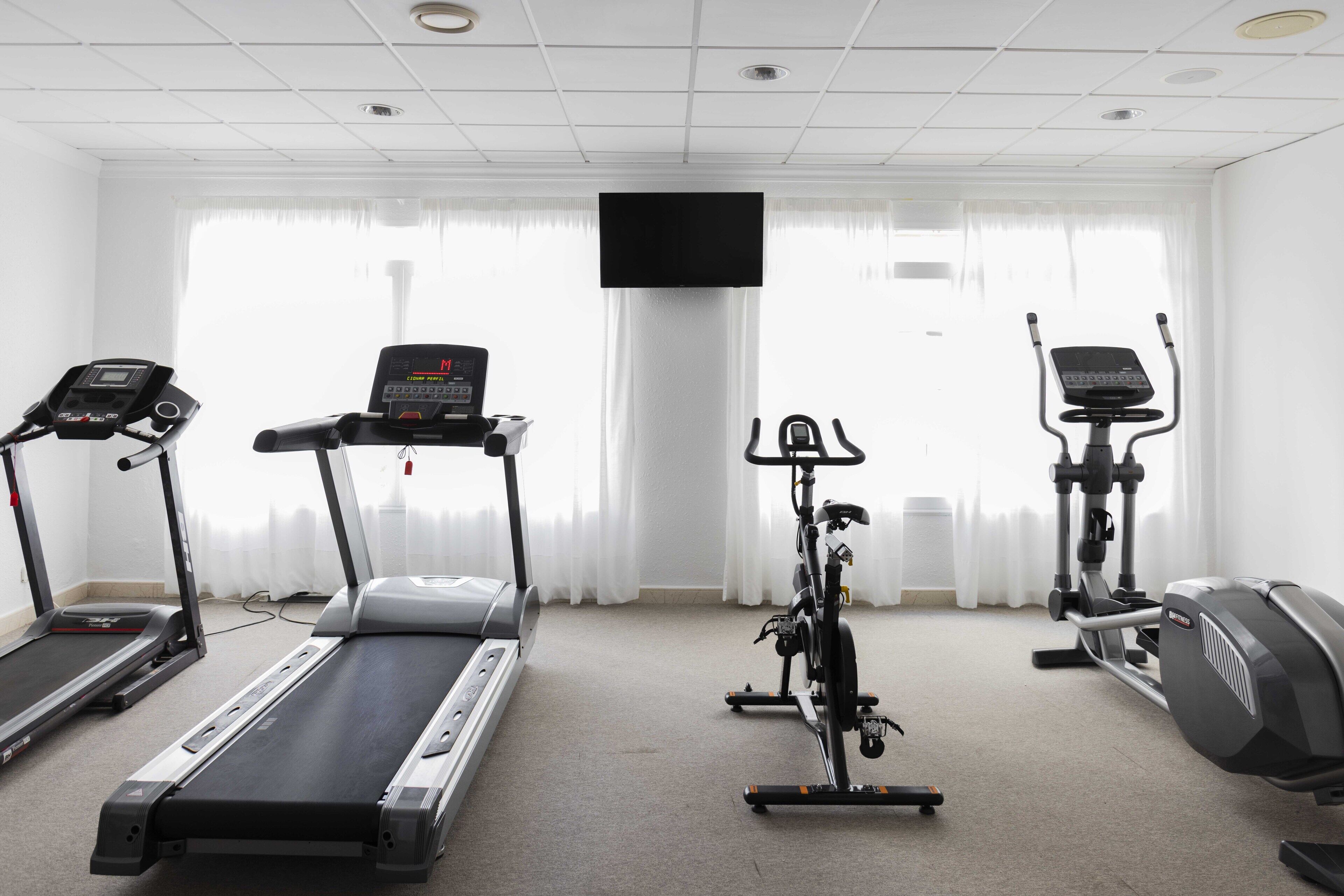 Une salle de remise en forme équipée de tapis de course, d’un vélo elliptique et d’un vélo d’appartement.