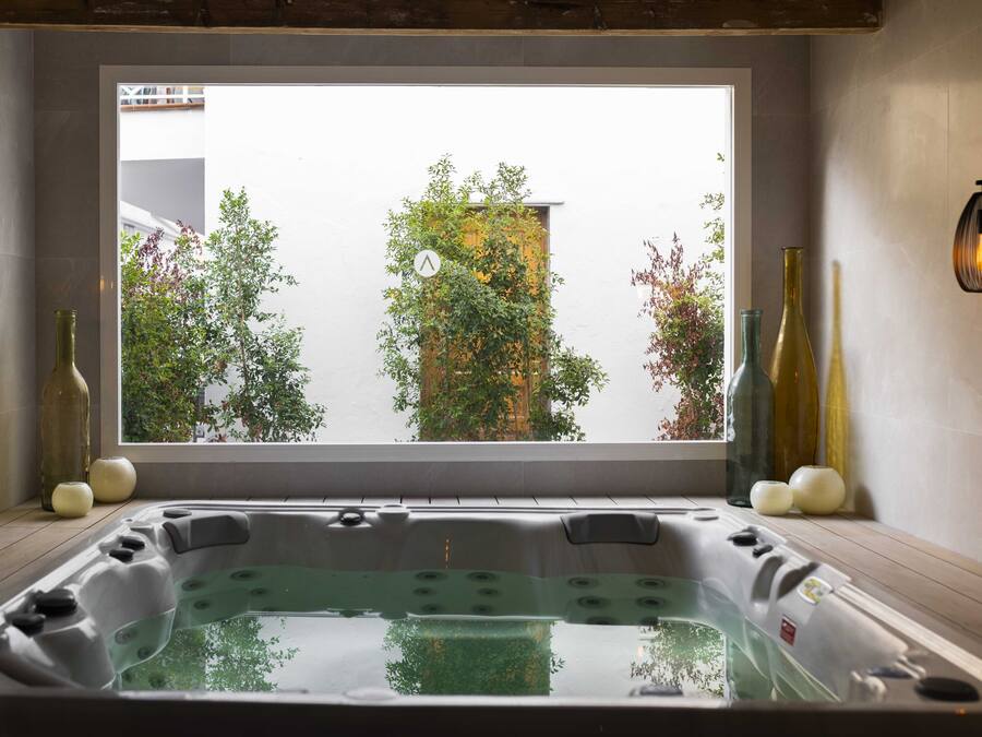A modern bathroom with a large window, a bathtub, and decorative bottles.