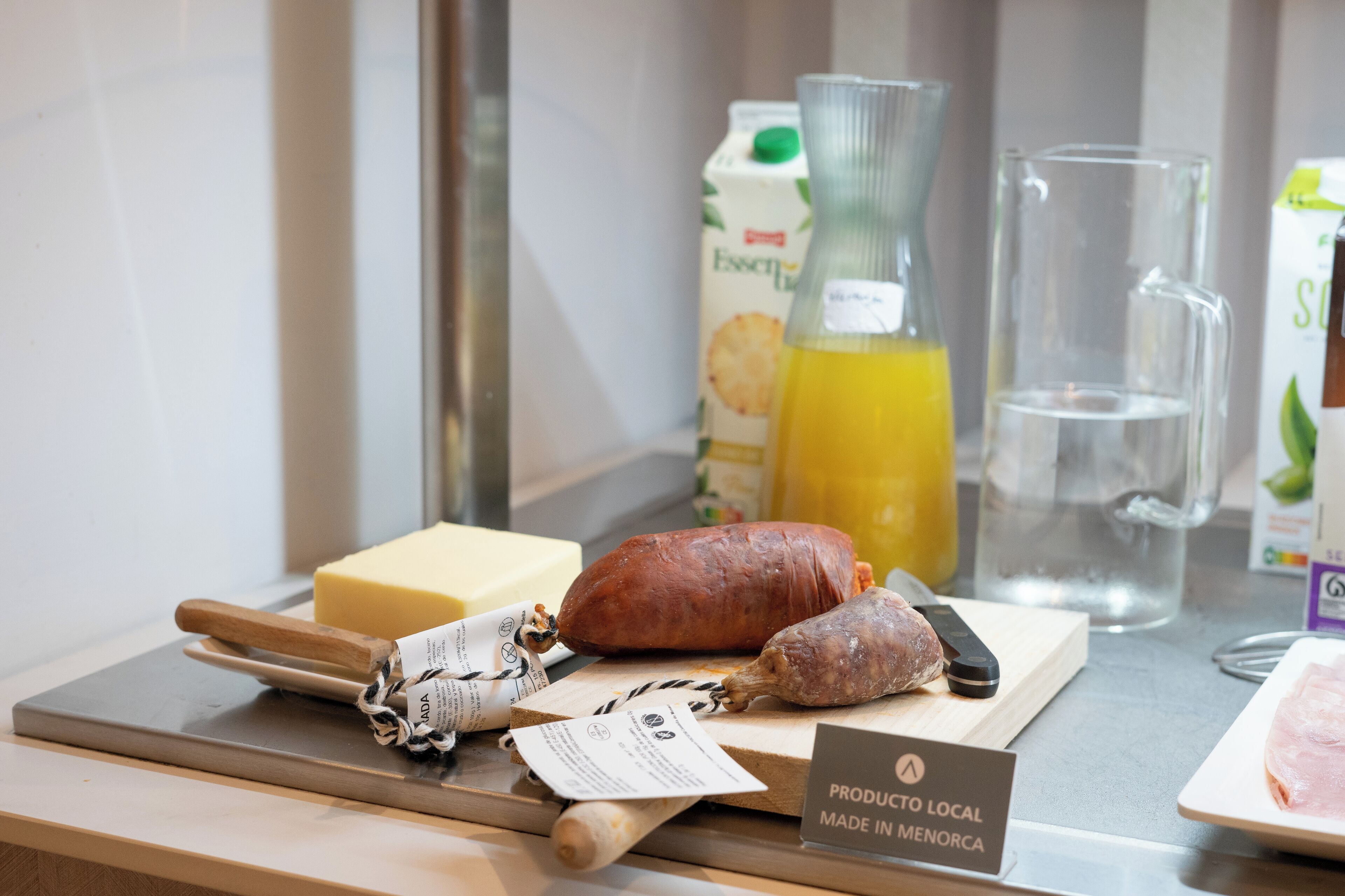 A selection of local products including cheese, cured meats, and a bottle of juice on a counter.