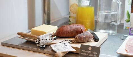 A selection of local products including cheese, cured meats, and a bottle of juice on a counter.