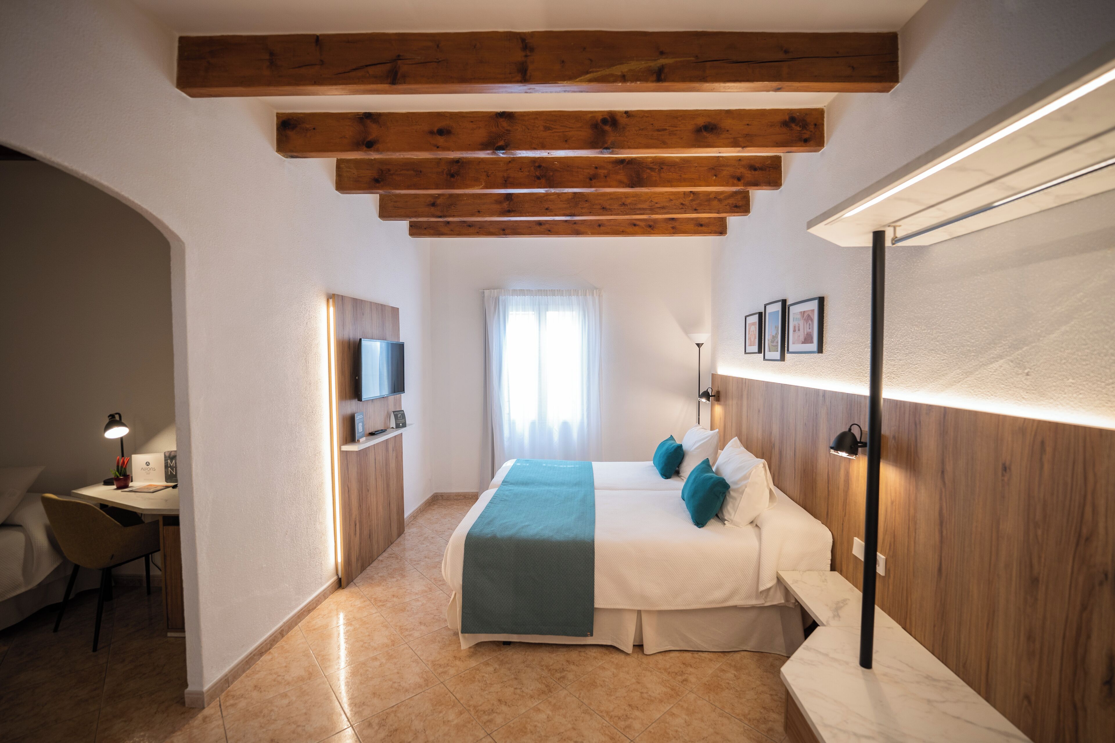 A bedroom with a bed, a desk, and a TV.