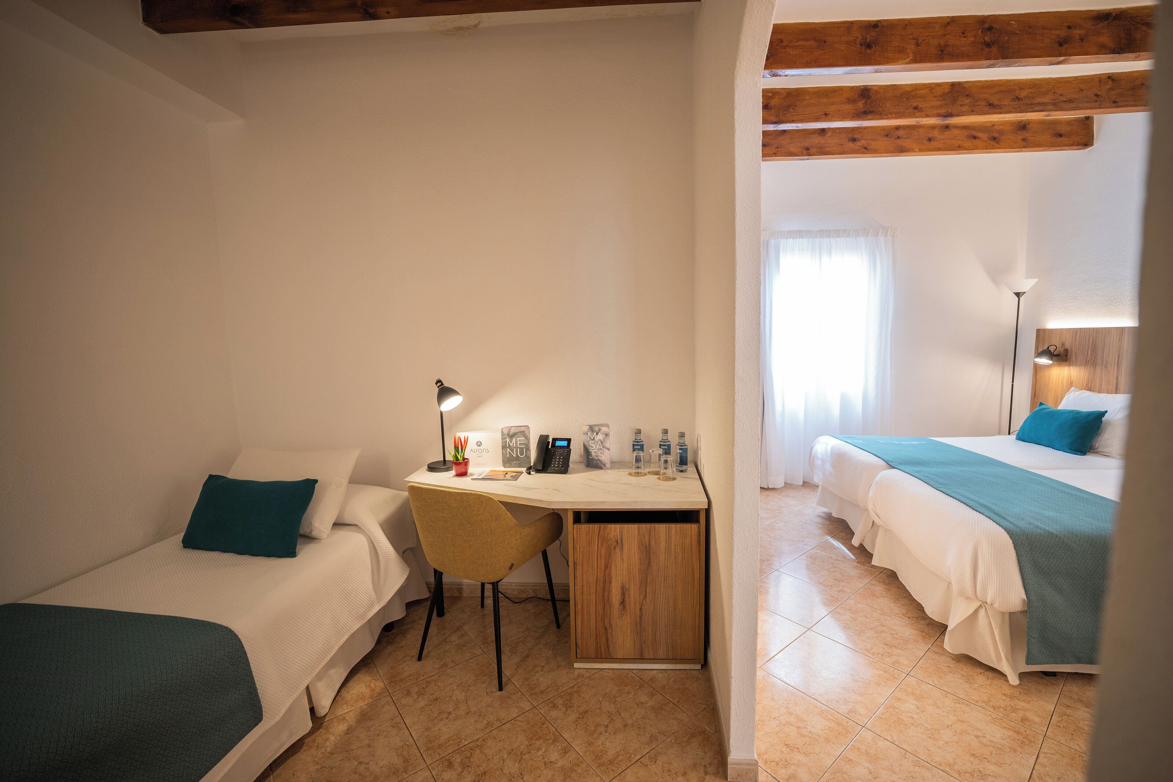 A bedroom with two beds, a desk, and a chair.