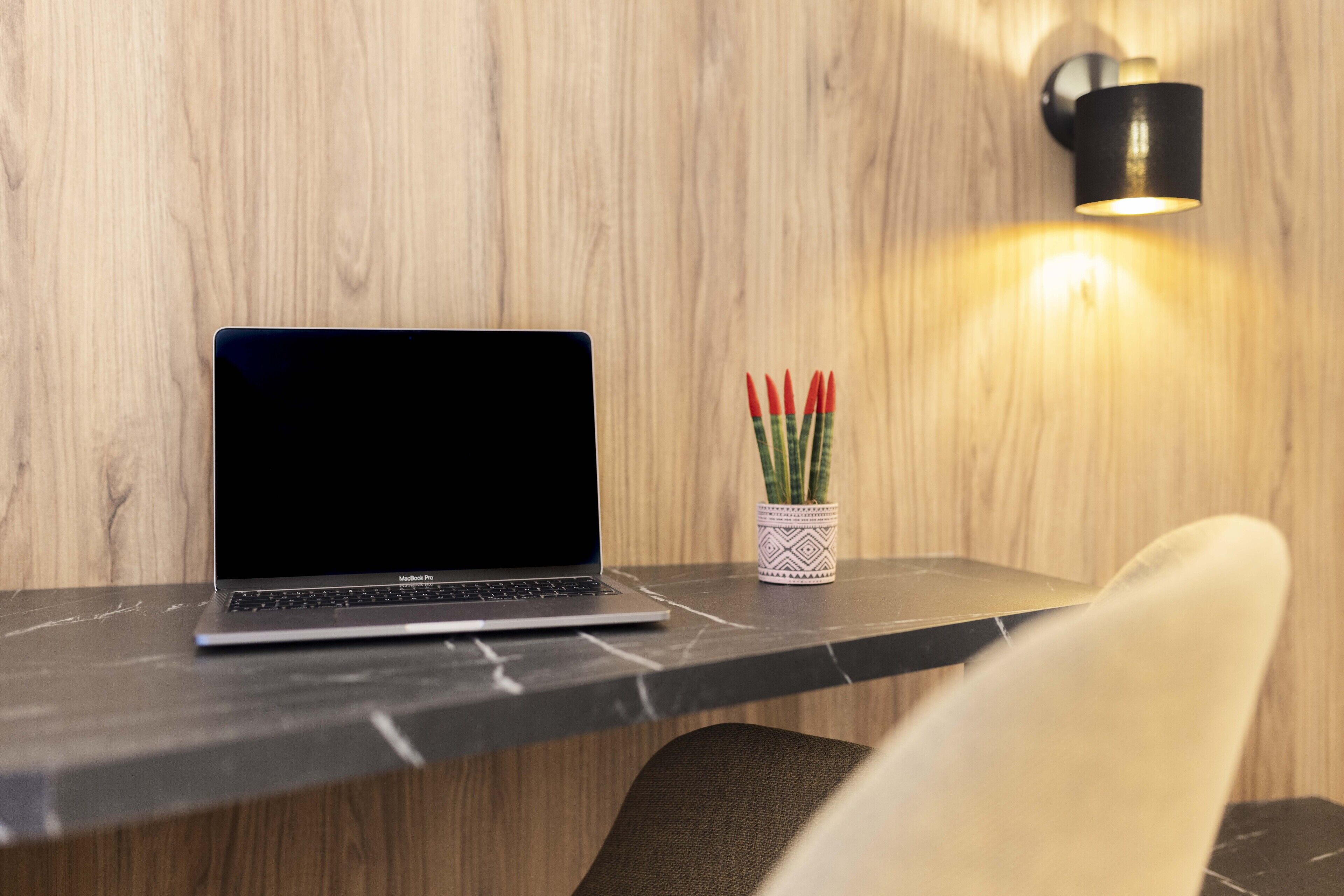Een laptop op een marmeren tafel, met een potplant ernaast.