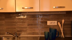 A kitchen with a stainless steel sink, a tiled backsplash, and wooden utensils on the counter. - Villa Campana (Torino)