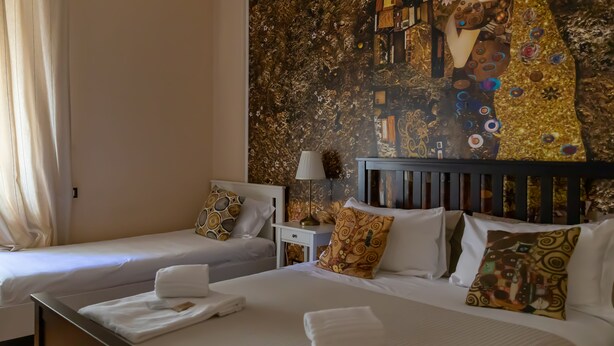 A hotel room with two beds, each with white linens and towels, a nightstand with a lamp, and a wall mural. - CENTRAL CITY (Genoa)