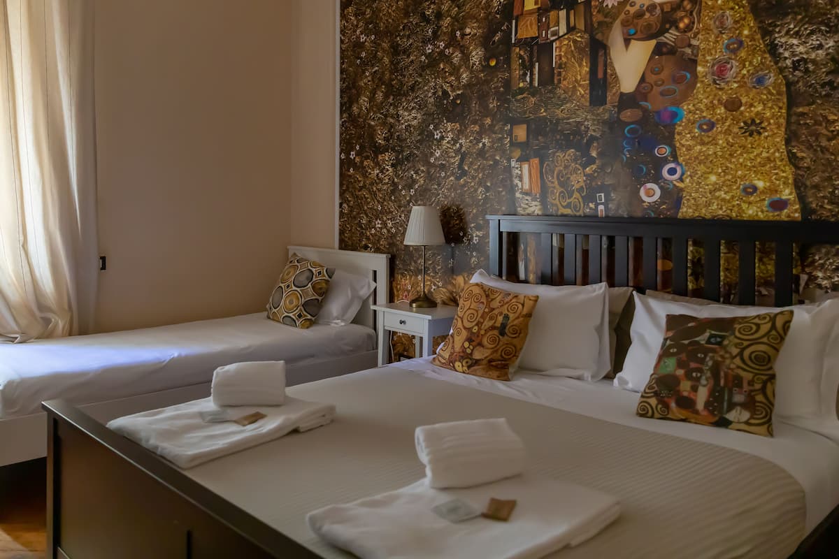 A hotel room with two beds, each with white linens and towels, a nightstand with a lamp, and a wall mural.