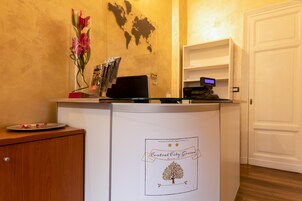 A reception desk with a world map, a flower vase, and a computer monitor.