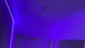 Käytävä, jossa on valkoinen ovi, patteri ja LED-valonauha.