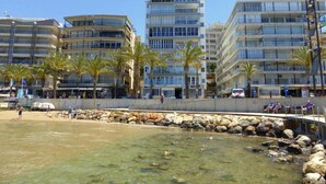 A beachfront hotel with multiple floors, palm trees, and a rocky shoreline. - Rentalmar Acantilados Playa (Salou)