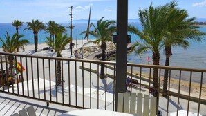 A balcony with a view of a beach, palm trees, and the sea. - Rentalmar Acantilados Playa (Salou)