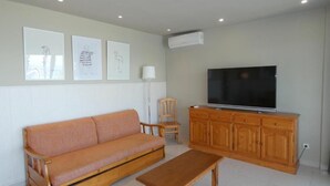 A living room with a sofa, a wooden table, a TV, and a cabinet. - Rentalmar Acantilados Playa (Salou)