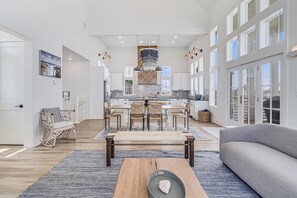 A spacious living area with a wooden coffee table, a grey sofa, and a dining area with a wooden table and chairs. - Unique & Charming Cinnamon Shore Home w/ Access to Resort-Like Amenities (Port Aransas)