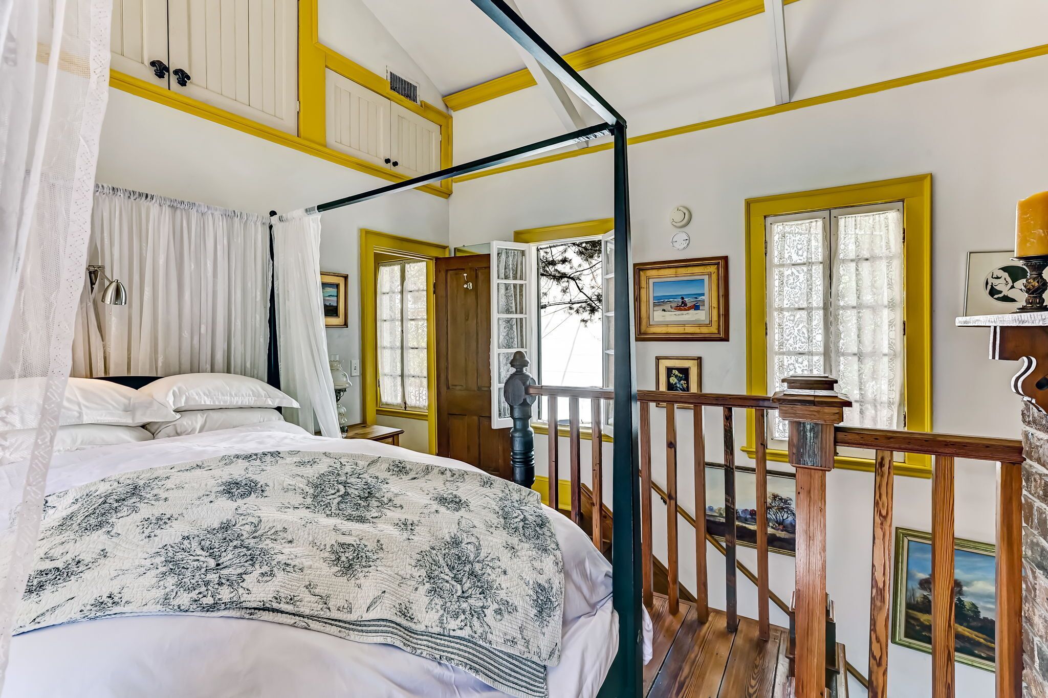 Un dormitorio con cama a dosel, vigas de madera en el techo y vistas al exterior a través de una ventana.