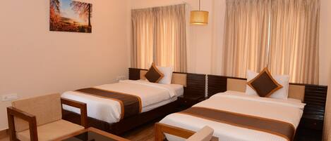 A hotel room with two beds, a sofa, a small table, and a painting on the wall.