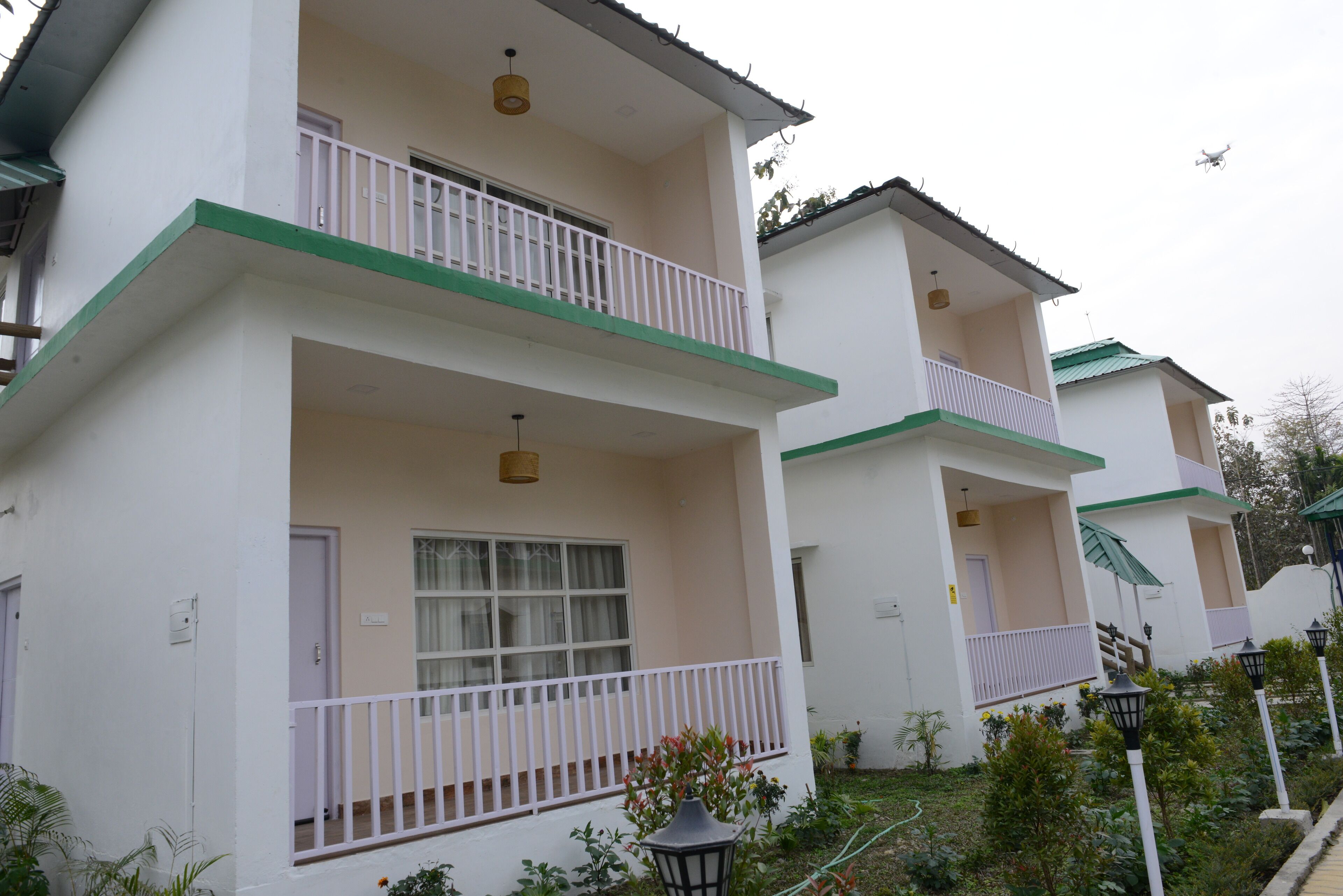 A row of white buildings with green trim and balconies, featuring a simple, clean architectural style.