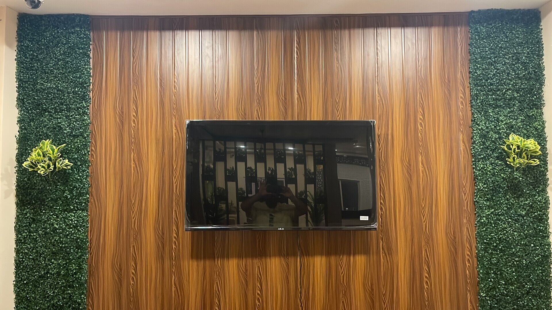 Un televisor de pantalla plana montado en una pared de madera con paneles verticales.