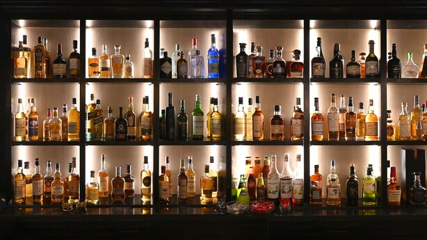 Un bar con numerosas estanterías llenas de botellas de licores.