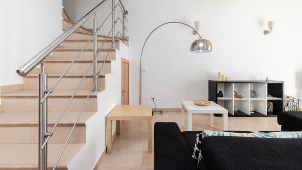 A modern living room with a staircase, a floor lamp, a coffee table, and a bookshelf. - Villa with parking in the center of the village by AlgarveManta (10V3) (Manta Rota)