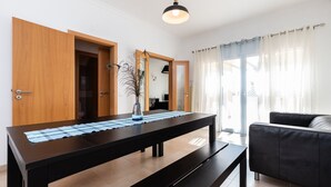 A modern living room with a dark wooden dining table, a black sofa, and a large mirror. - Villa with parking in the center of the village by AlgarveManta (10V3) (Manta Rota)
