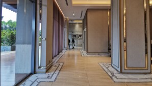 A modern hotel lobby with a marble floor, large doors, and a view of the outdoors.