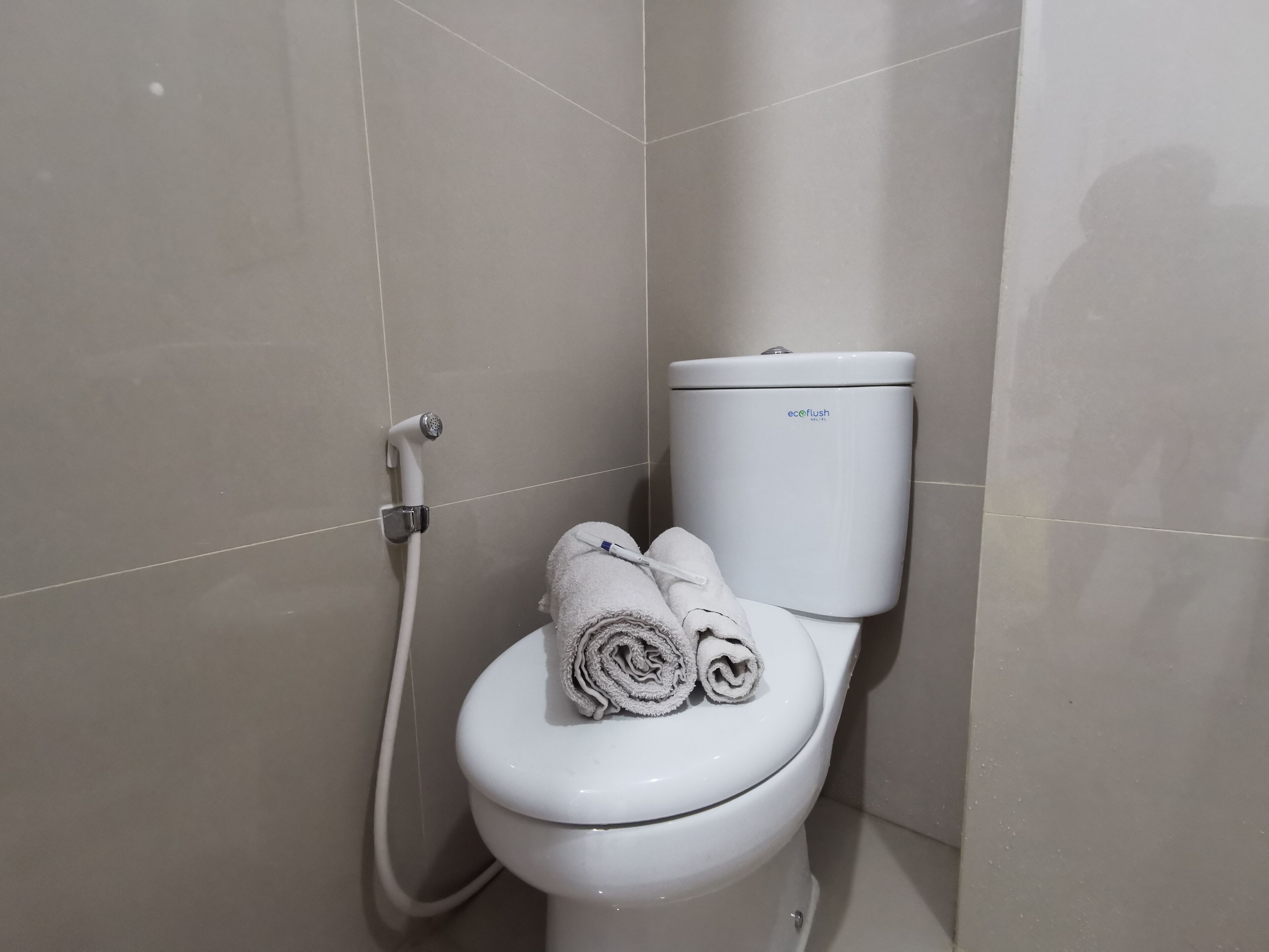 Des toilettes blanches, avec un porte-rouleau de papier toilette et une serviette posée sur le dessus.