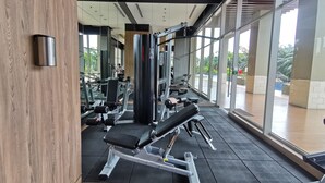 A modern gym with various exercise equipment, large windows, and a view of the outdoors.