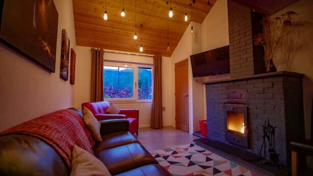 A cozy living room with a fireplace, a red sofa, and a geometric rug.