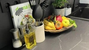A kitchen counter with a marble surface, a bowl of fruit, a potted plant, and kitchen utensils. - NordiK 2 - Beautiful apartment close to science (València)