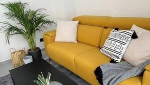A living room with a mustard yellow sofa, a black coffee table, and a potted plant. - NordiK 2 - Beautiful apartment close to science (València)