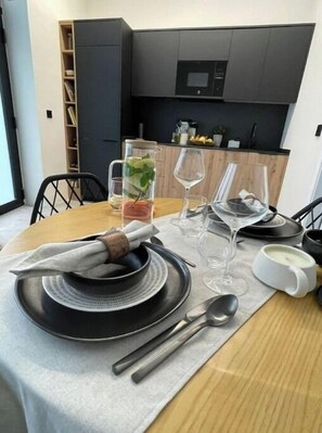 A dining area with a table set for two, featuring black plates, clear wine glasses, and a candle holder. - NordiK 2 - Beautiful apartment close to science (València)