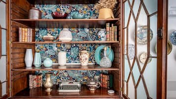 Un meuble en bois doté d’étagères où sont rangés des livres, des vases décoratifs et une machine à écrire.