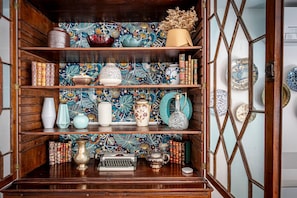 Un meuble en bois doté d’étagères où sont rangés des livres, des vases décoratifs et une machine à écrire.