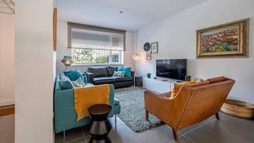 A modern living room with a sofa, a coffee table, a TV, and a painting on the wall.