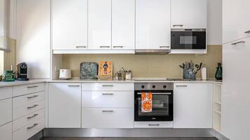 A modern kitchen with white cabinets, a stove, an oven, and a microwave.