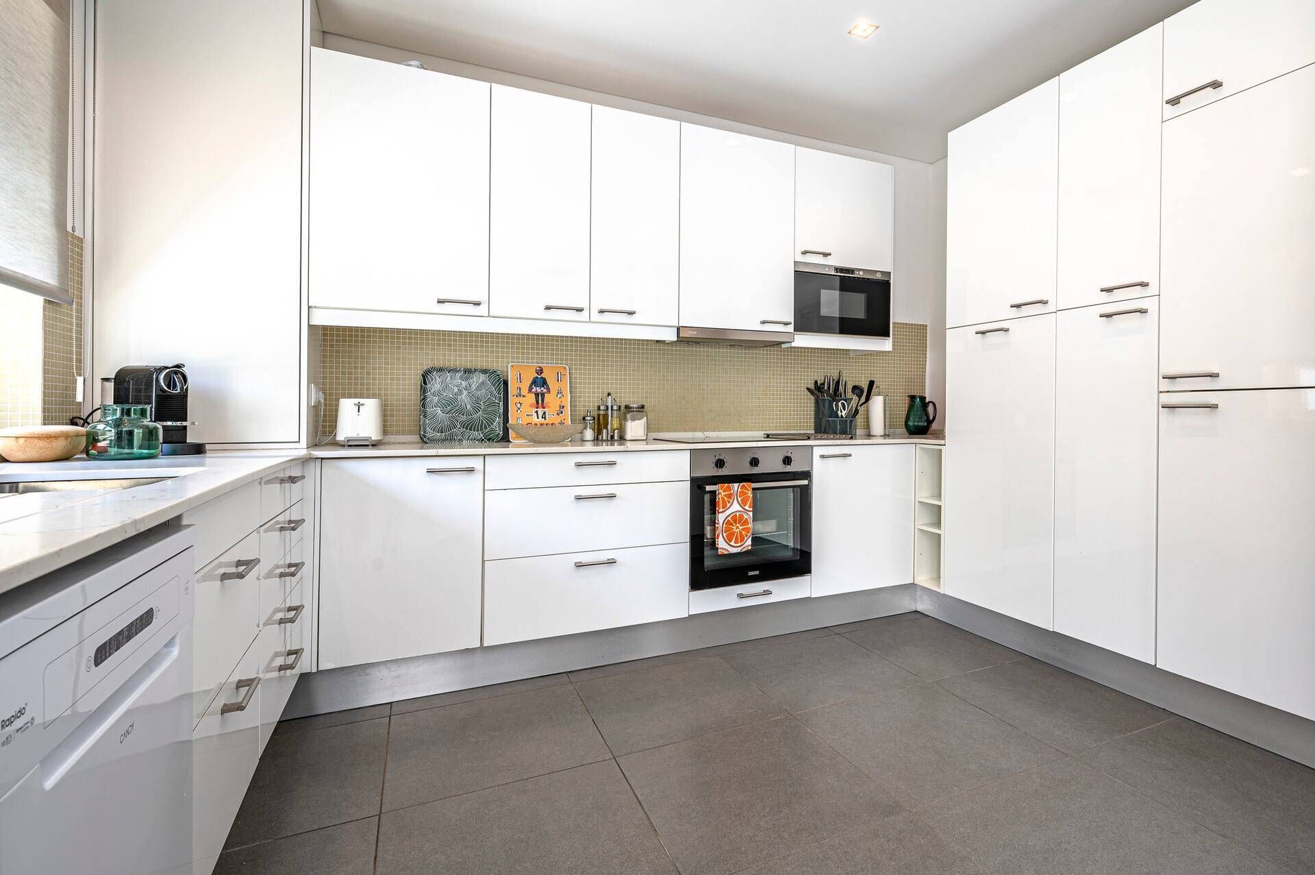 A modern kitchen with white cabinets, a built-in oven, and a microwave.