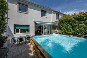Ein modernes Haus mit Swimmingpool, Außenbereich und überdachter Terrasse.