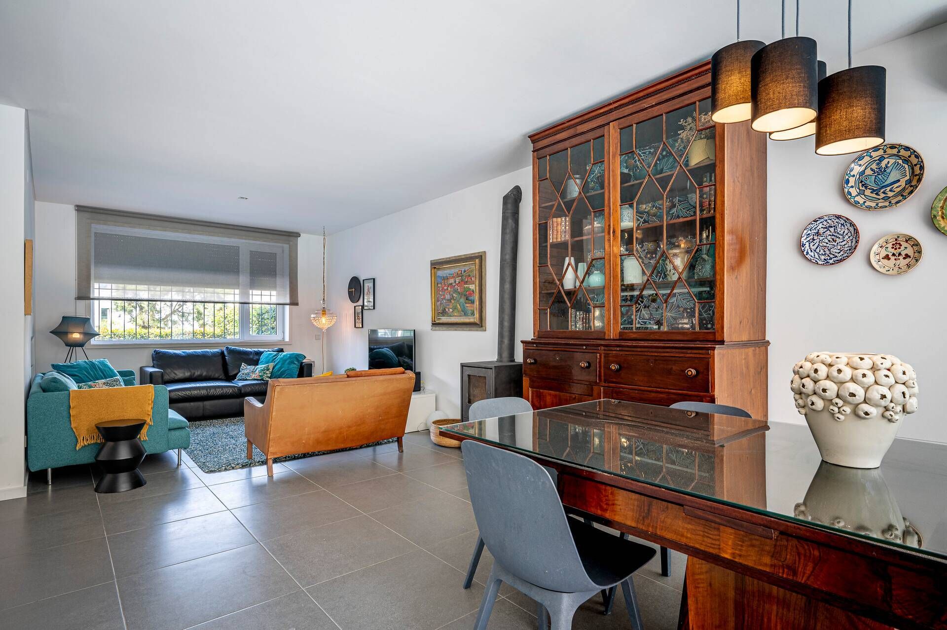 A modern living room with a sofa, a dining table, and a cabinet with glass doors.