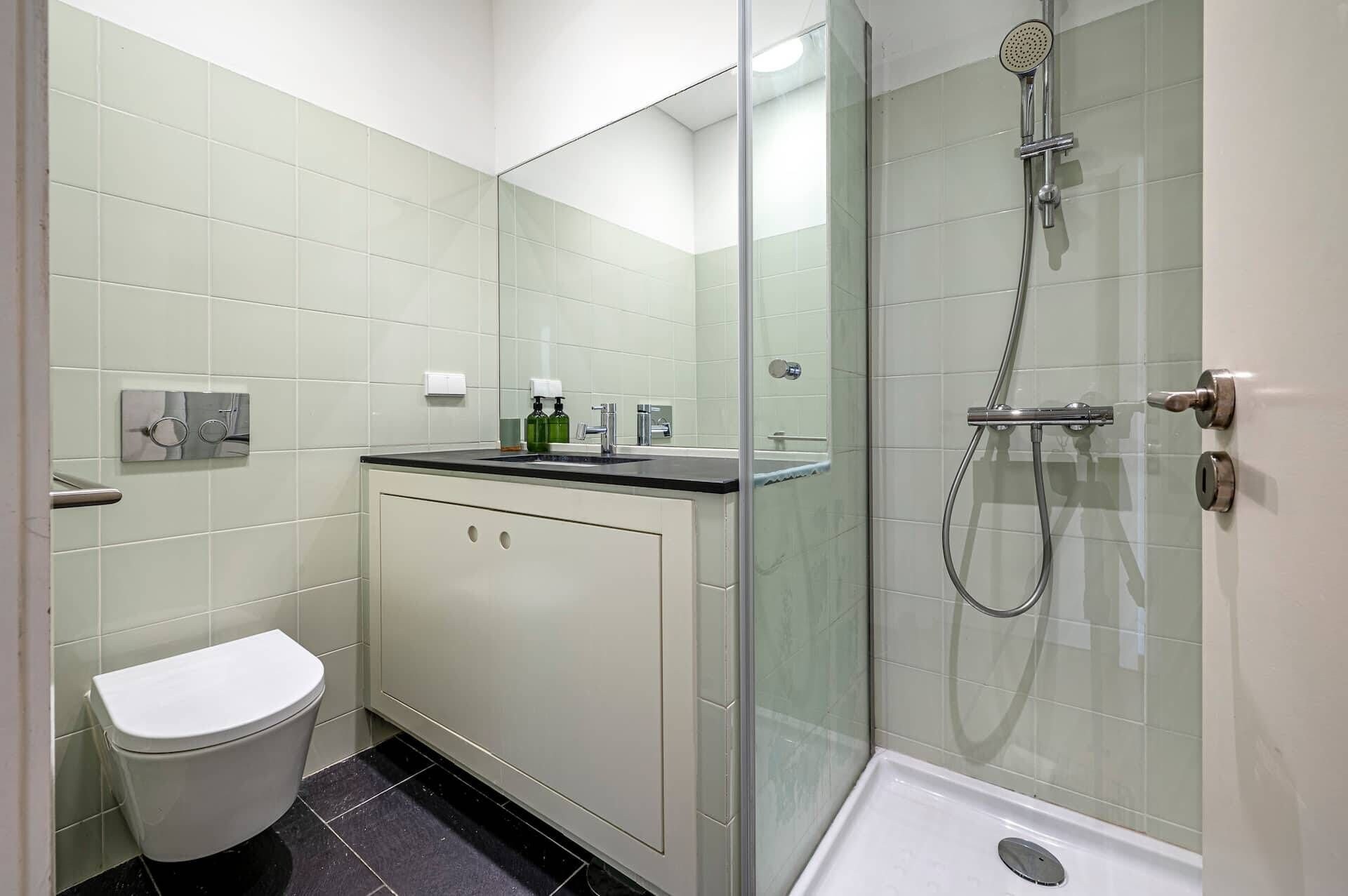 Un bagno moderno con cabina doccia in vetro, un water e un lavabo con specchio.