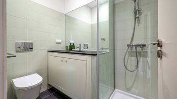 Un bagno moderno con cabina doccia in vetro, un water e un lavabo con specchio.