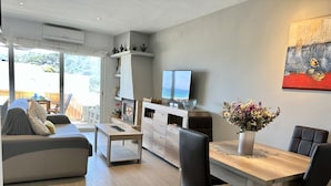 Een moderne woonkamer met een bank, een salontafel, een eettafel met stoelen, een televisie en een decoratieve vaas.