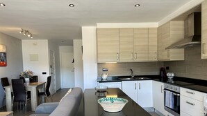 Een moderne keuken met lichte houten kastjes, een zwart aanrecht en roestvrijstalen apparatuur.