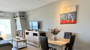 Een moderne woonkamer met een eethoek, een flatscreen-tv en een schilderij aan de muur.