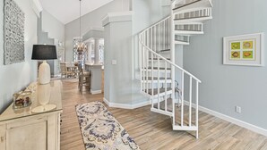 Ein modernes Interieur mit einer Wendeltreppe, einem Essbereich und einem Gang, der zu einem anderen Raum führt.