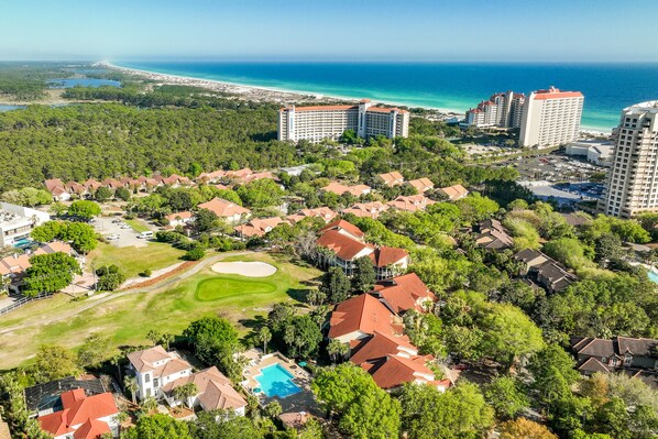 A resort with multiple buildings, a golf course, and a beach view.