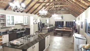 A spacious kitchen with a large island, wooden cabinets, and a thatched ceiling.