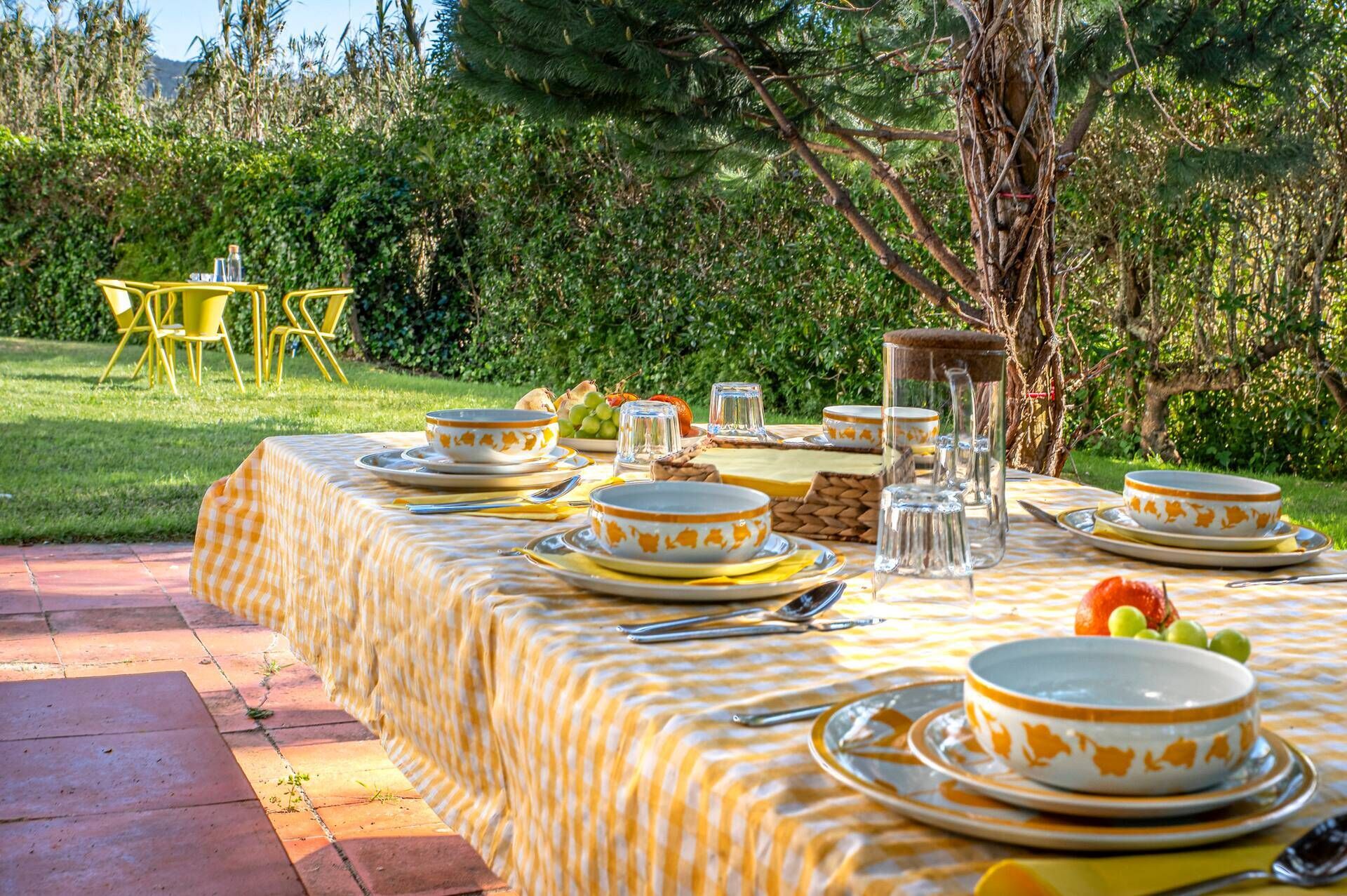 Un área de comedor al aire libre con una mesa lista para una comida, rodeada de follaje.