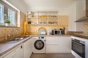 A compact kitchen with a built-in washing machine, a microwave, and a coffee maker.